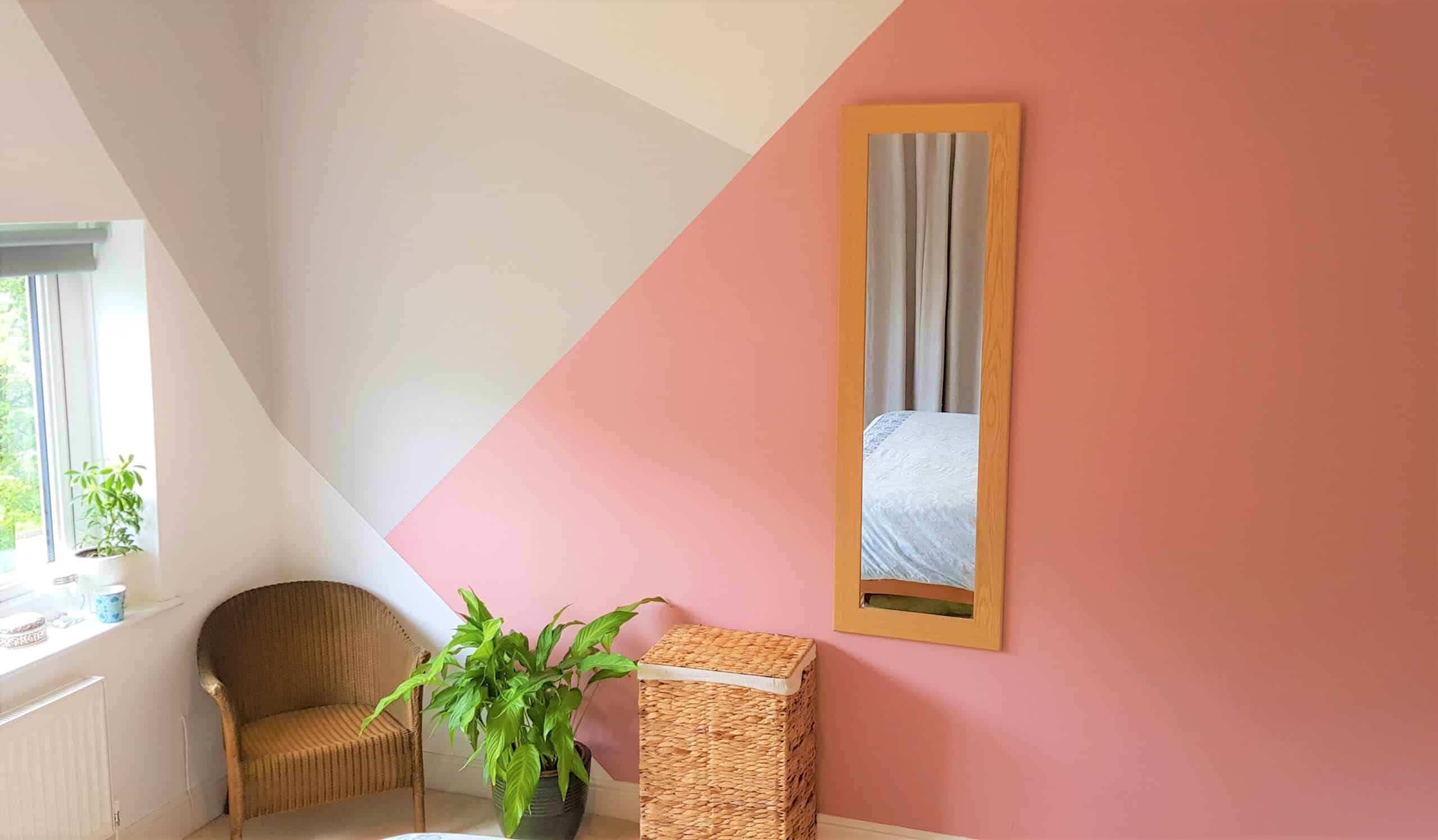 bedroom with geometric wall painting with shades of pink and cream