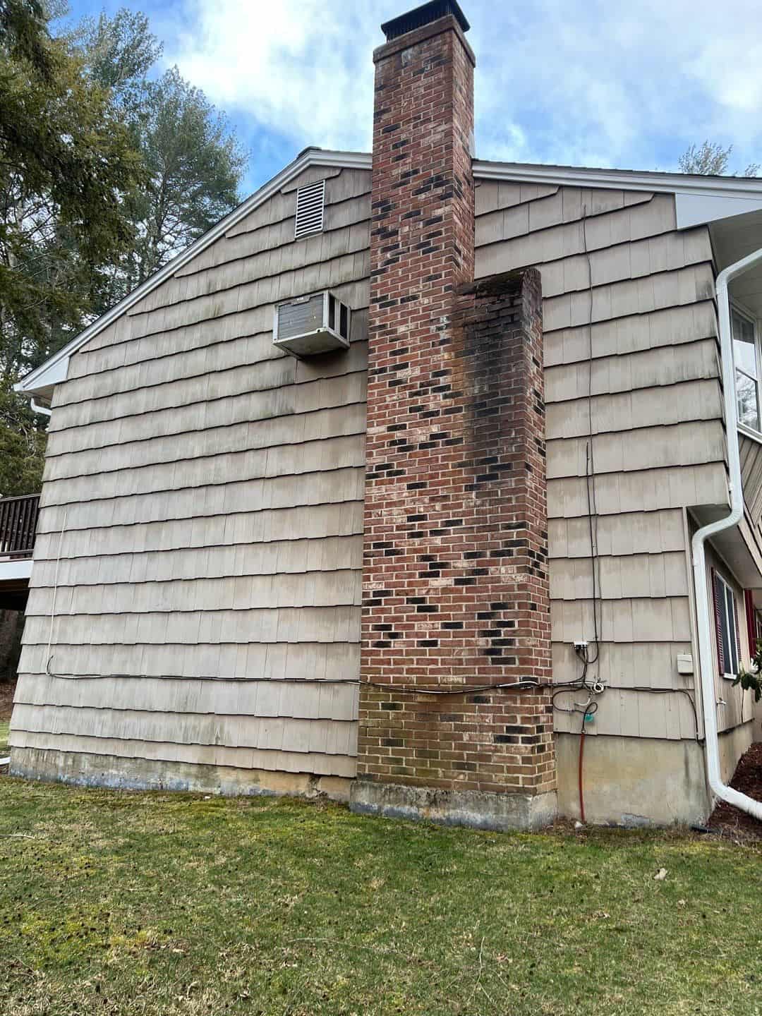 exterior of a house with a brick chimney before high-pressure cleaning